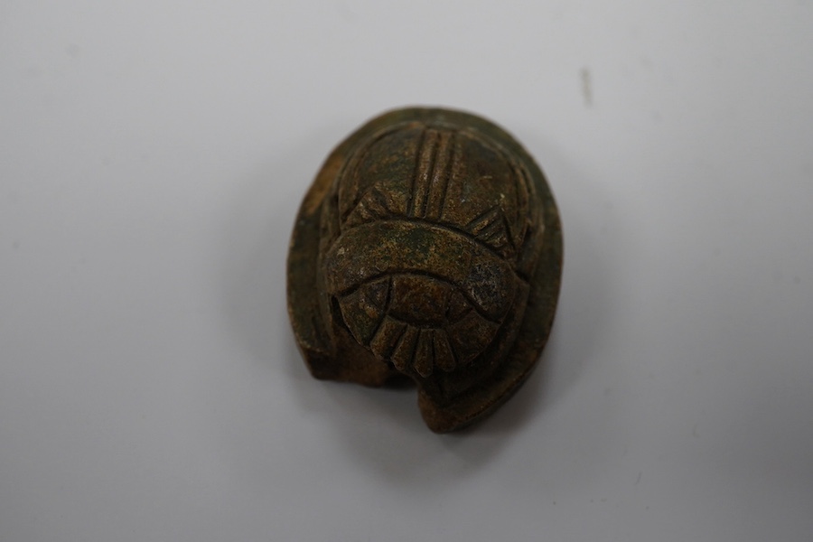 Three ancient Egyptian carved stone ushabti, tallest 15cm, with carved hieroglyphs to the body, together with a seated figure, possibly of Isis, a scarab and a yellow metal brooch with inset stone carved with hieroglyphs